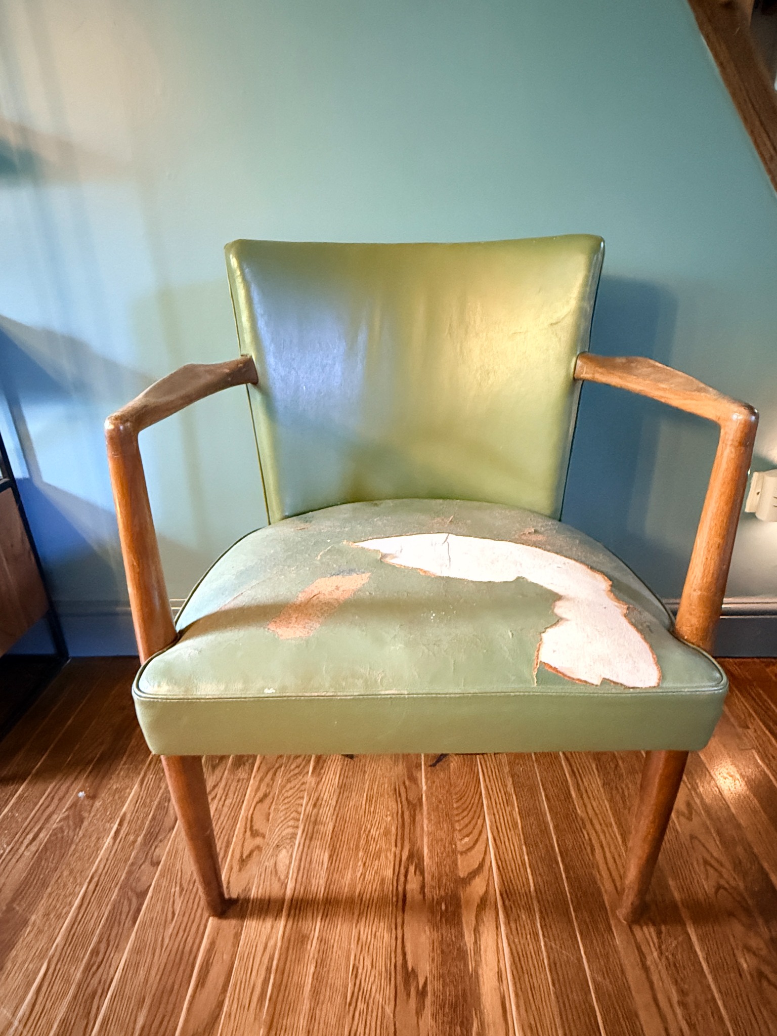 Chair before restoration with worn green upholstery